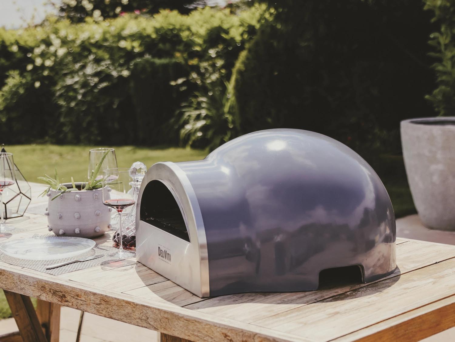 Eleganter grauer Delivita Outdoor-Ofen, perfekt für stilvolles Kochen im Freien. Kompakt, effizient und hochwertig designt.
