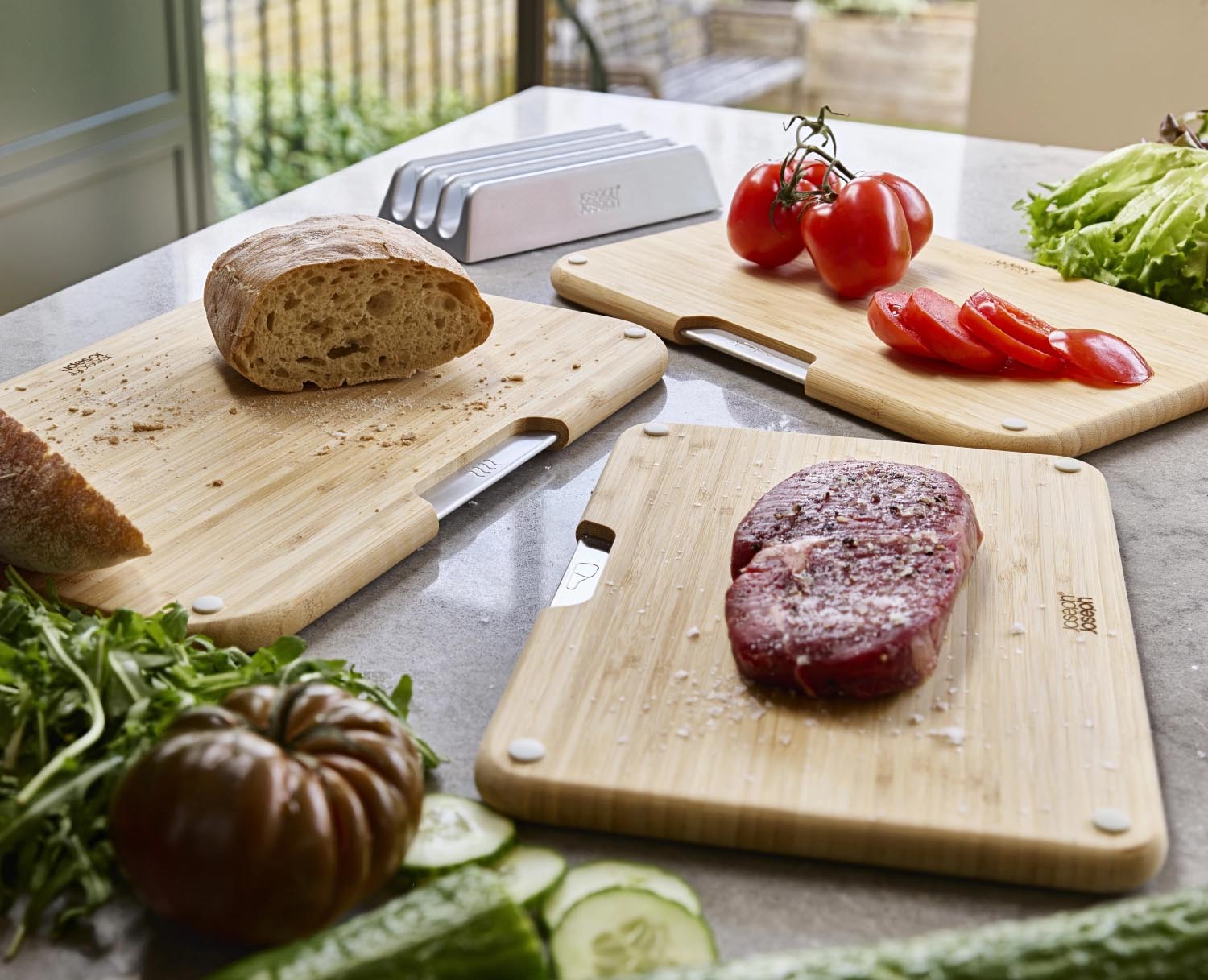 Entdecken Sie das 3er Set Nest Boards von Joseph Joseph: stilvolle, zweiseitige Bambus-Schneidbretter mit praktischem Halter für hygienische Küchenarbeit.