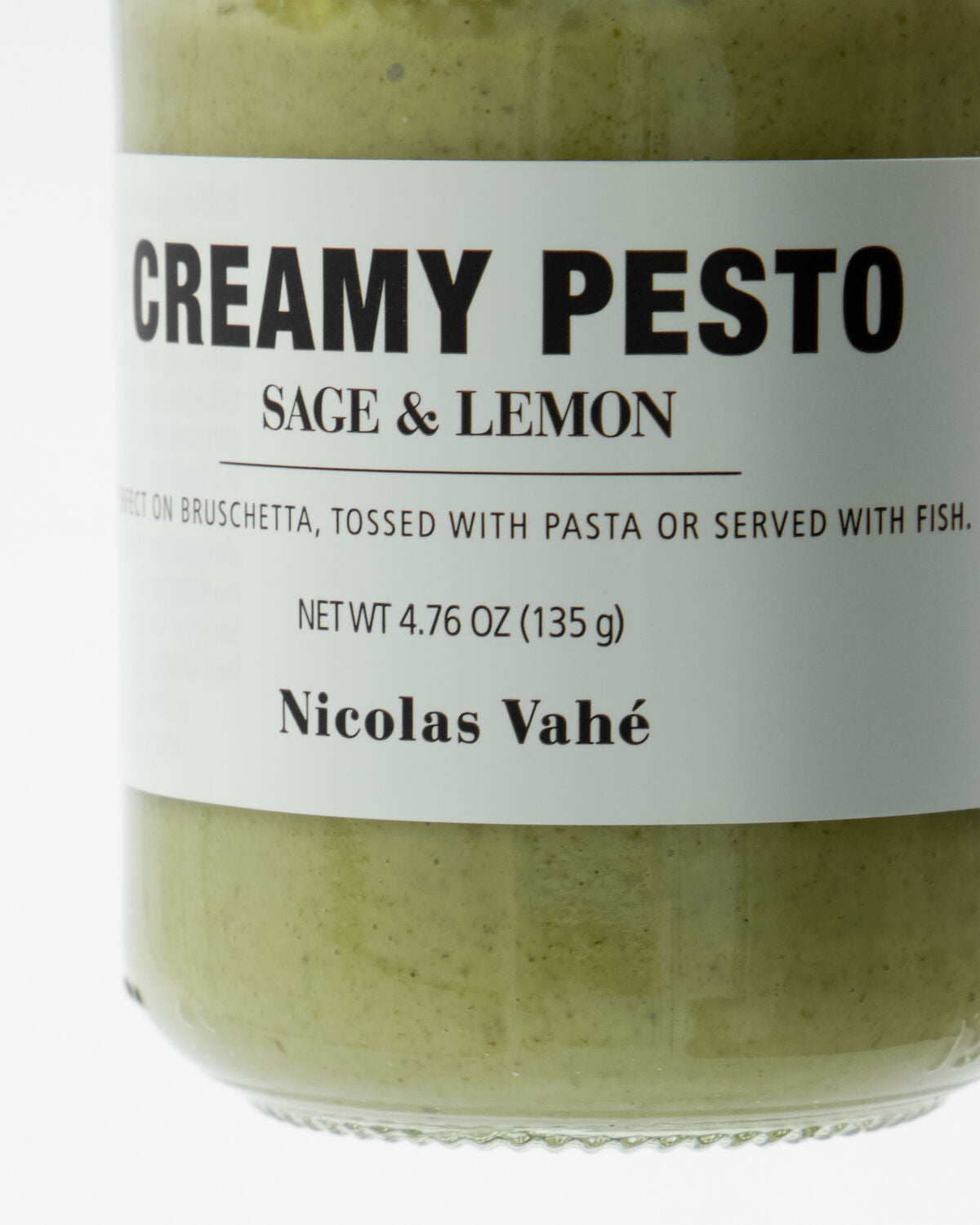 Ein elegantes Glas mit cremigem Pesto, verfeinert mit Salbei und Zitrone, 135 g, ansprechend auf einem rustikalen Holzbrett arrangiert.