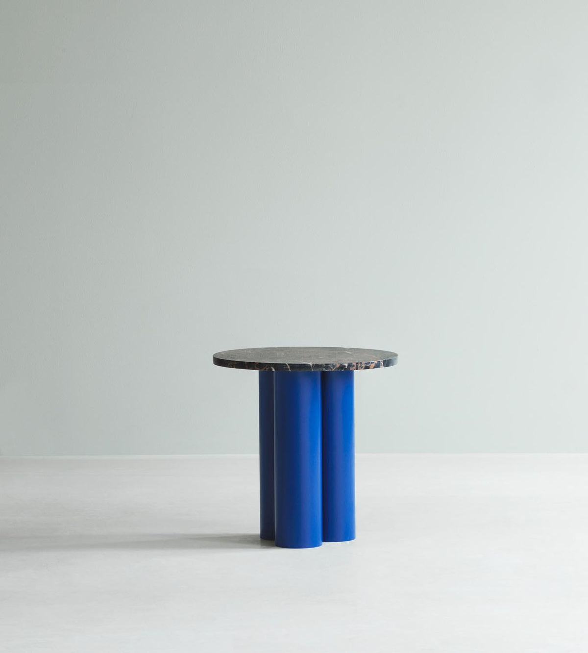 Beistelltisch Dit von Normann Copenhagen mit runder Tischplatte aus Stein in Sand Travertine Light, getragen von drei zylindrischen Stahlbeinen.