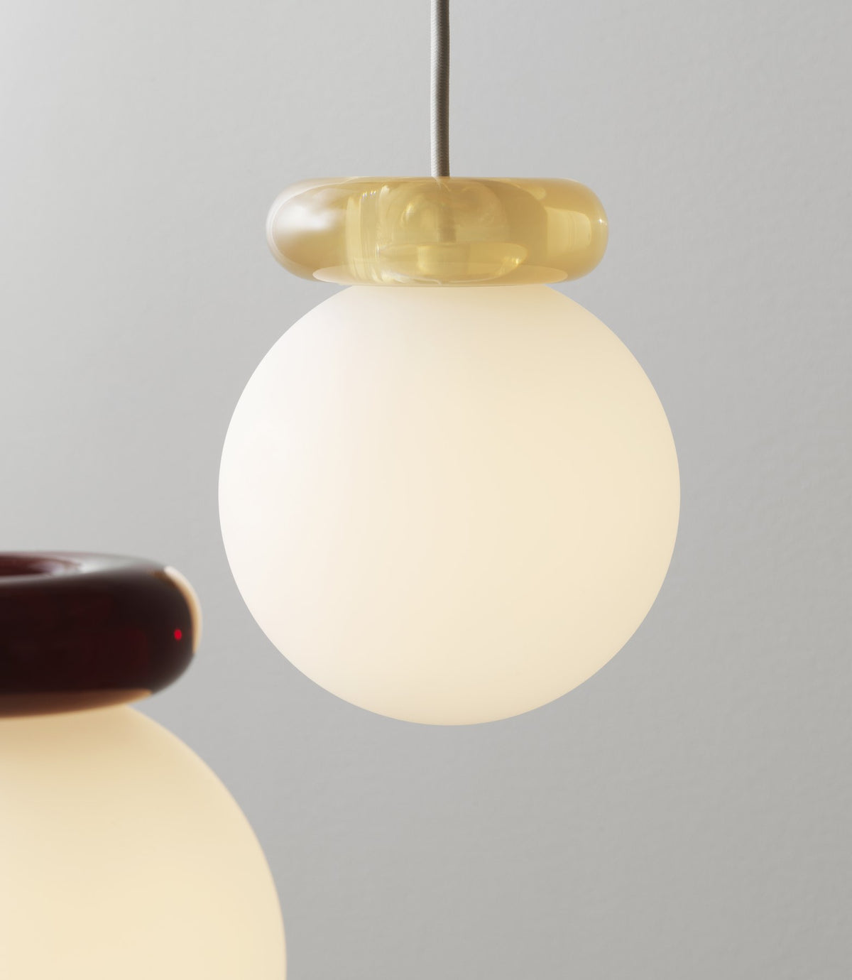 Pendelleuchte Hinx von Normann Copenhagen in Dunkelbraun, Lampenschirm aus Opalglas mit ringförmigem Kunstharzsockel.