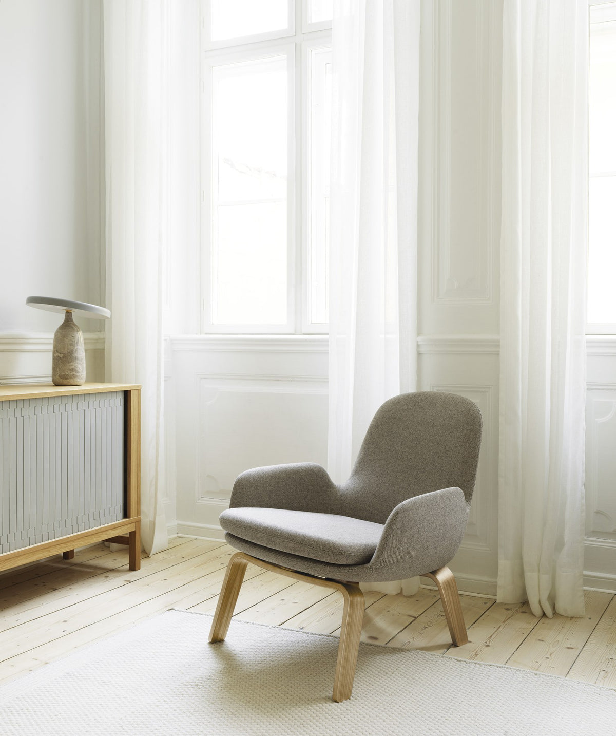 Era Lounge-Sessel von Normann Copenhagen in Grau mit Eichenbeinen, gepolsterter Sitzschale und geschwungener Rückenlehne.