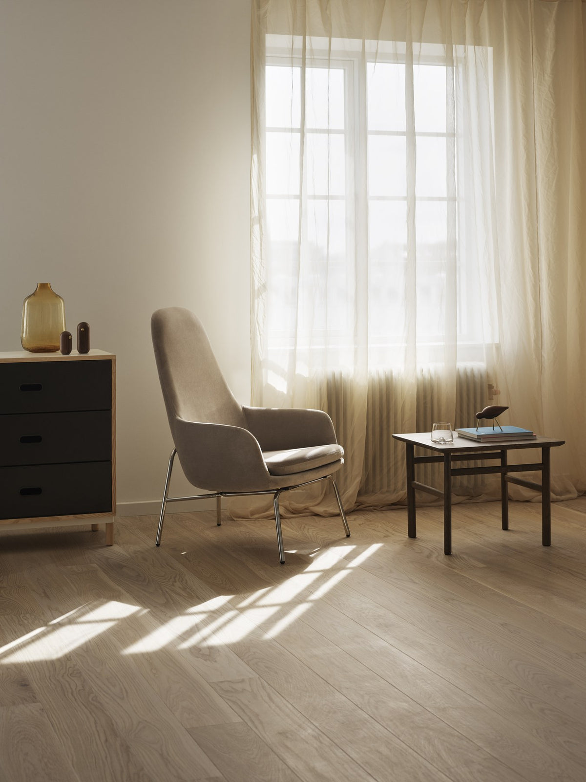 Era Lounge-Sessel hoch mit Stahlgestell, Farbe Cognac, geschwungene Sitzschale mit gepolstertem Kissen und schwarzen Stahlbeinen von Normann Copenhagen.