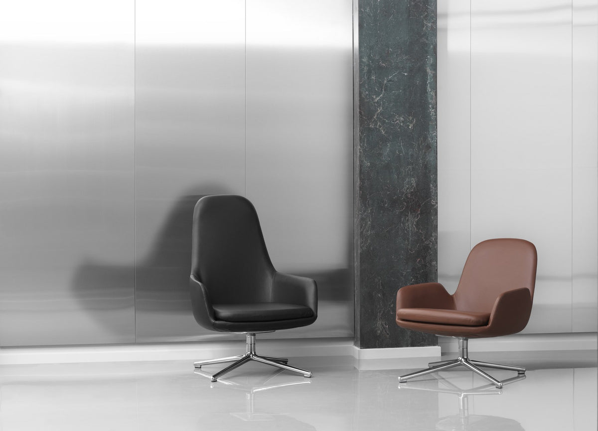 Era Lounge-Sessel hoch mit Stahlgestell, Farbe Cognac, geschwungene Sitzschale mit gepolstertem Kissen und schwarzen Stahlbeinen von Normann Copenhagen.
