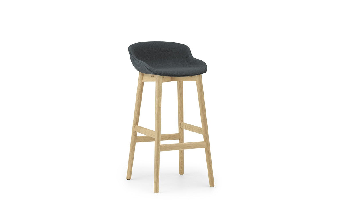 Hyg Barhocker von Normann Copenhagen mit vollgepolsterter Sitzschale aus Polypropylen, Gestell aus lackierter Eiche, Sitzhöhe 75 cm.