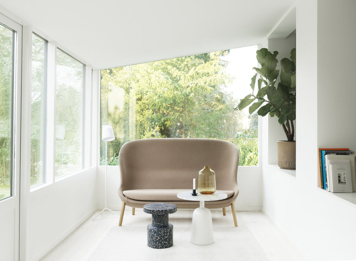 Hyg 2er Sofa von Normann Copenhagen in Beige mit Beinen aus schwarzer Eiche, geschwungene Form mit hohen Seitenteilen und breiter Sitzfläche.