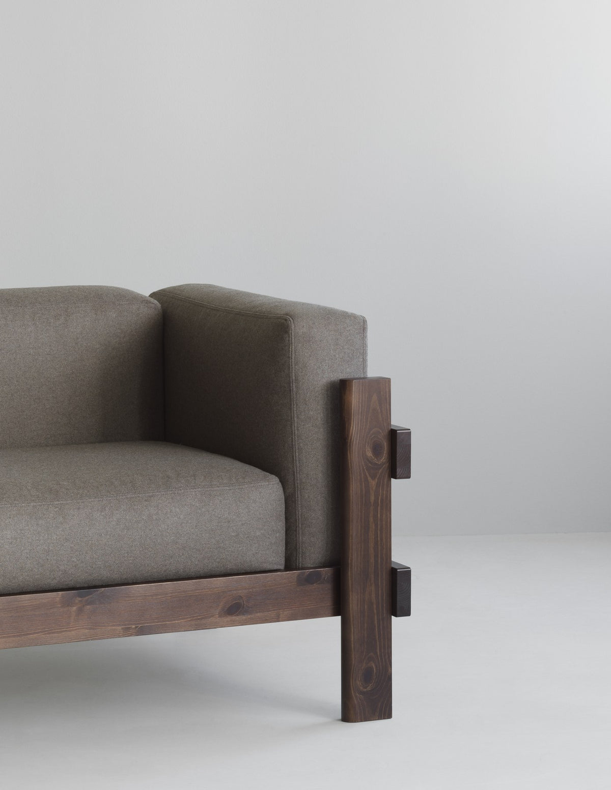 Kube 3er Sofa in Anthrazit von Normann Copenhagen mit sichtbarem Kiefernholz-Rahmen und lose aufliegenden Polsterkissen.
