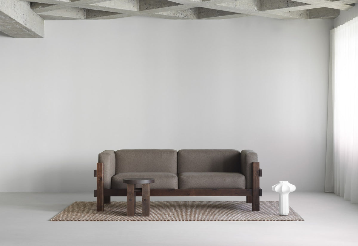 Kube 3er Sofa in Anthrazit von Normann Copenhagen mit sichtbarem Kiefernholz-Rahmen und lose aufliegenden Polsterkissen.