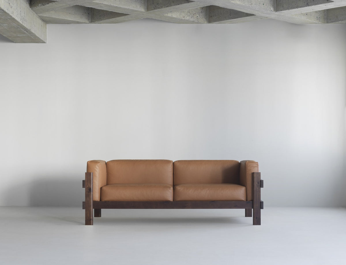 Kube 3er Sofa in Anthrazit von Normann Copenhagen mit sichtbarem Kiefernholz-Rahmen und lose aufliegenden Polsterkissen.