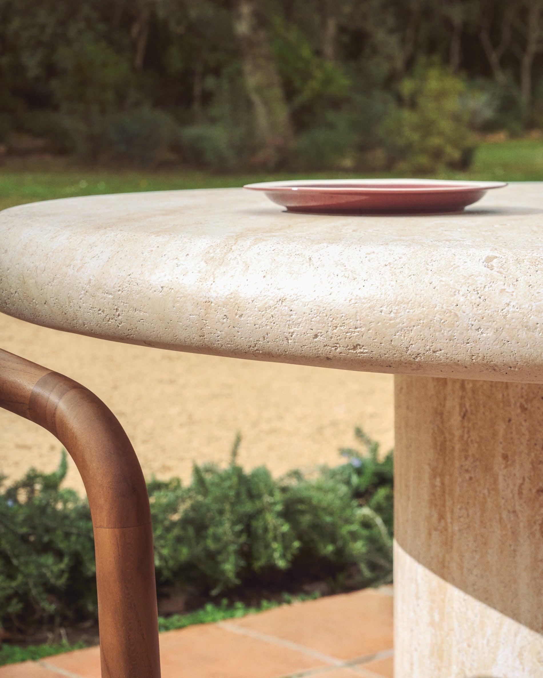 Moderner runder Tisch Drasi aus robustem Zement mit ansprechender Travertinoberfläche, Ø 122 cm, perfekt für Garten und Terrasse.