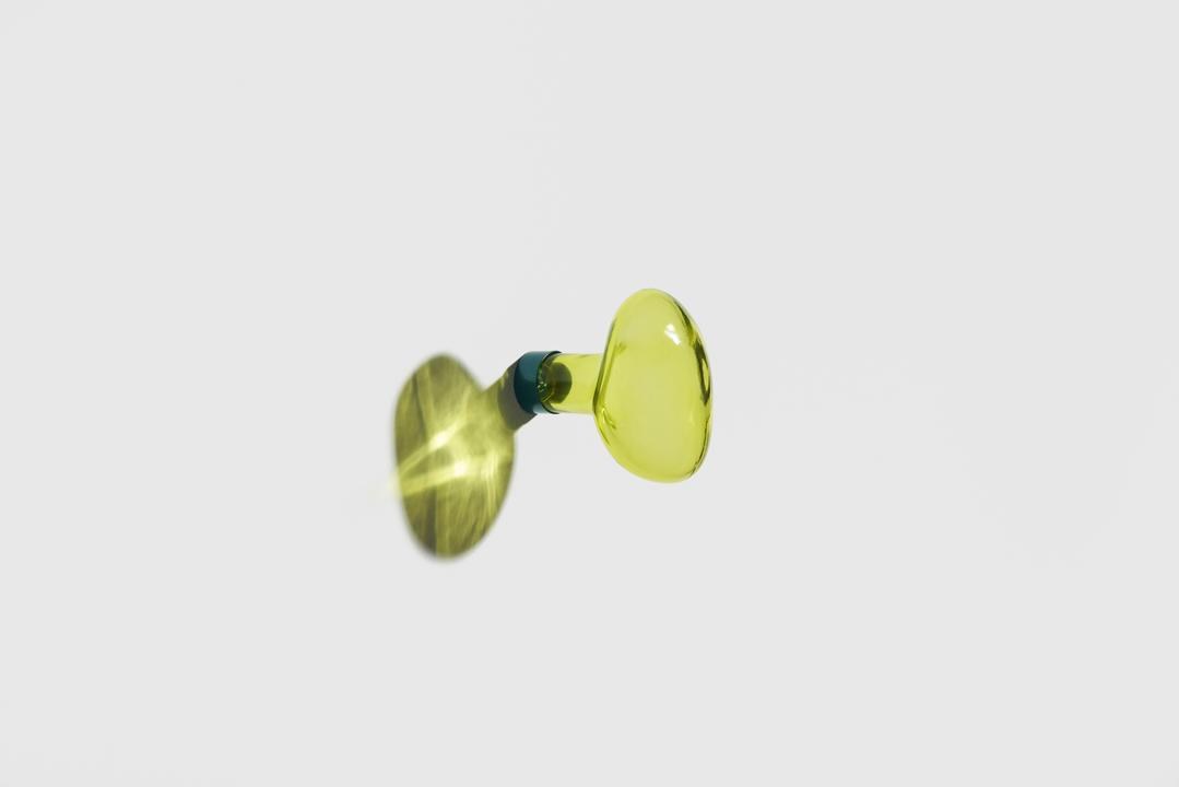 Kleiderhaken Bubble in Limette aus mundgeblasenem, lackiertem Glas mit rundem Blasen-Design und mattem Stahl-Befestigungssystem an weisser Wand.