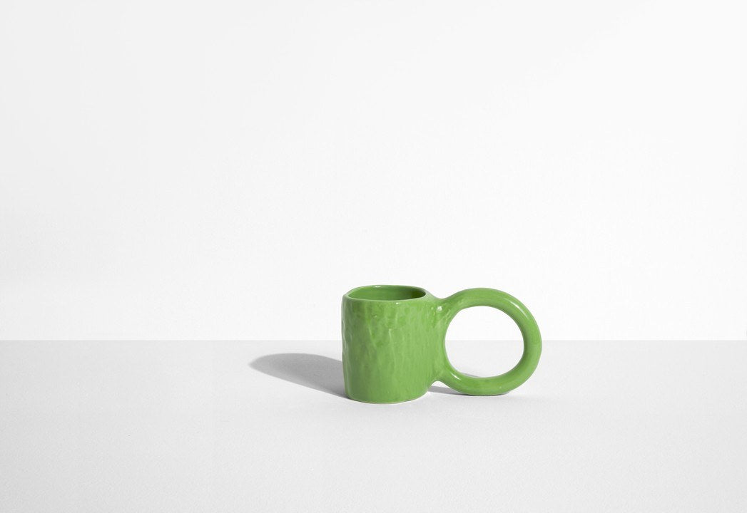 Keramiktasse Donut in Pistazie mit glasierter Oberfläche und donutförmigem Henkel, mittlere Grösse, handwerklicher Look, auf hellem Hintergrund.