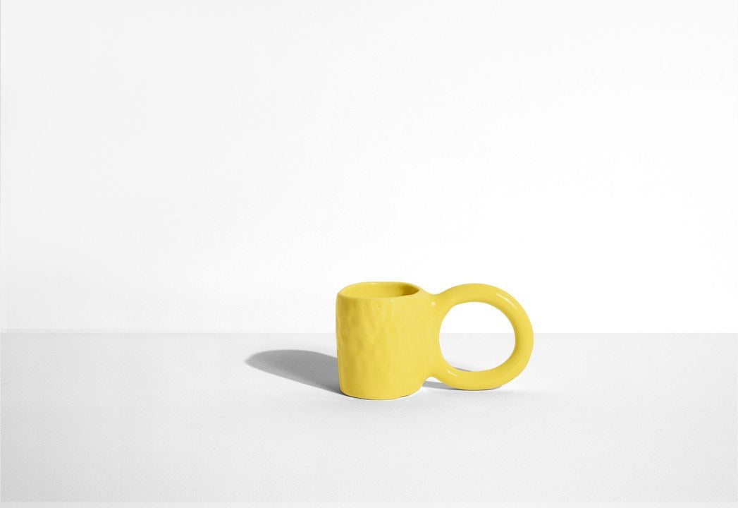 Keramiktasse Donut in Pistazie mit glasierter Oberfläche und donutförmigem Henkel, mittlere Grösse, handwerklicher Look, auf hellem Hintergrund.