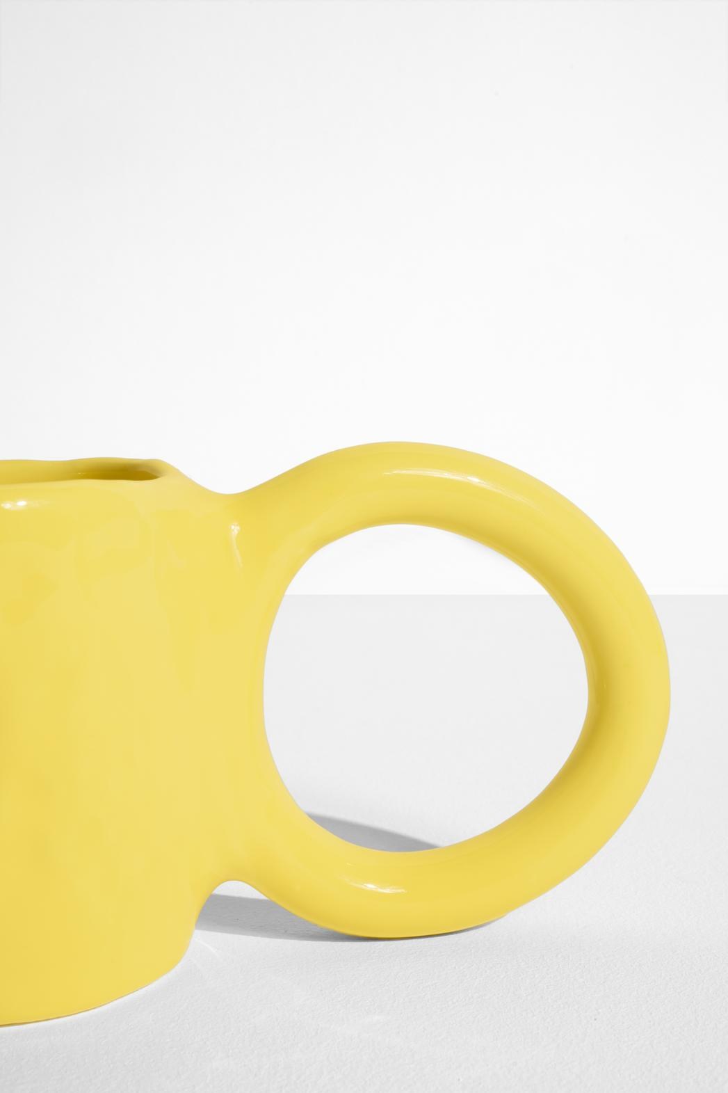 Keramiktasse Donut in Pistazie mit glasierter Oberfläche und donutförmigem Henkel, mittlere Grösse, handwerklicher Look, auf hellem Hintergrund.