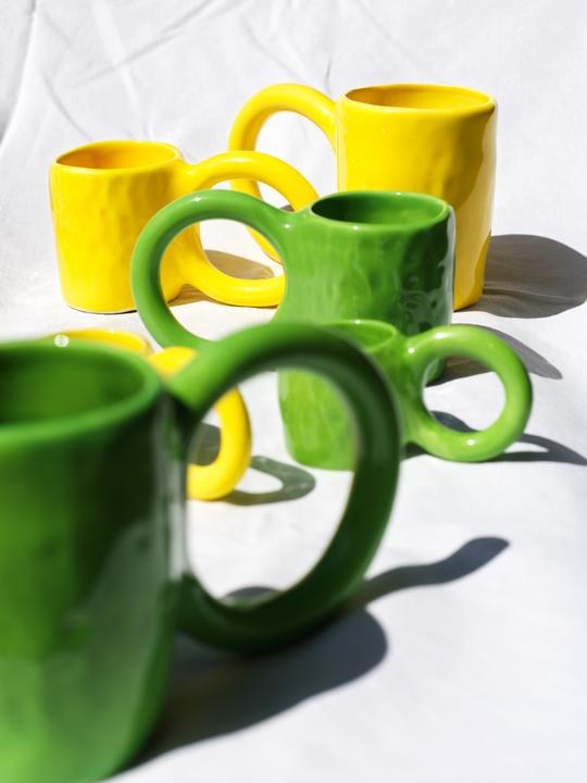 Keramiktasse Donut in Pistazie mit glasierter Oberfläche und donutförmigem Henkel, mittlere Grösse, handwerklicher Look, auf hellem Hintergrund.