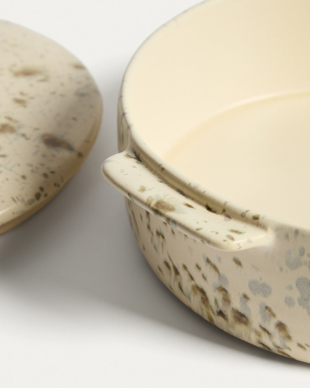 Weisse Auflaufform aus Keramik mit braunem Aufdruck und Deckel, gesprenkeltes Finish durch reaktive Glasur, rechteckige Form für den gedeckten Tisch.