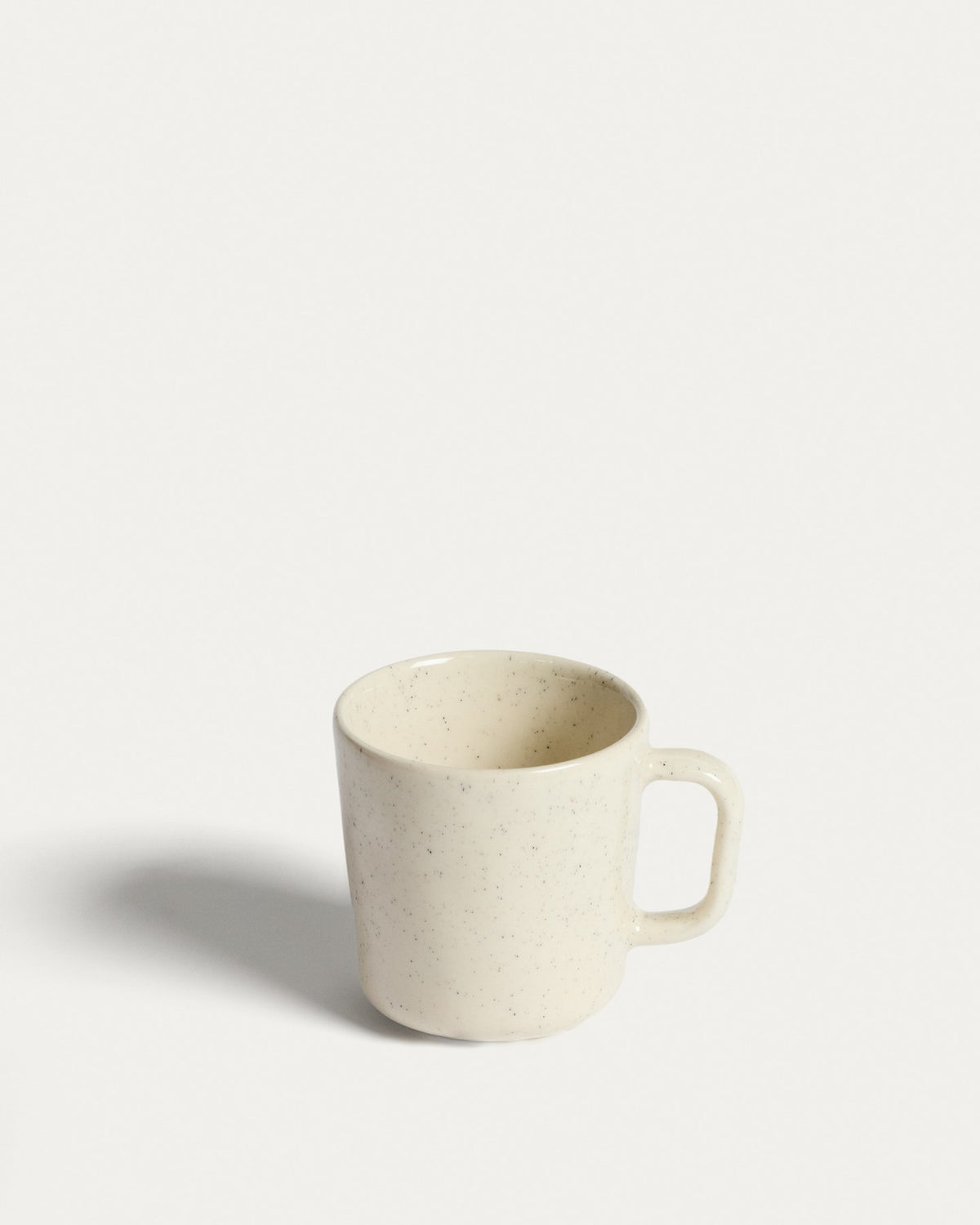 Weisse Tasse Daner aus glänzender Keramik mit schlichter, runder Form und leicht beiger Färbung, fotografiert vor neutralem Hintergrund.
