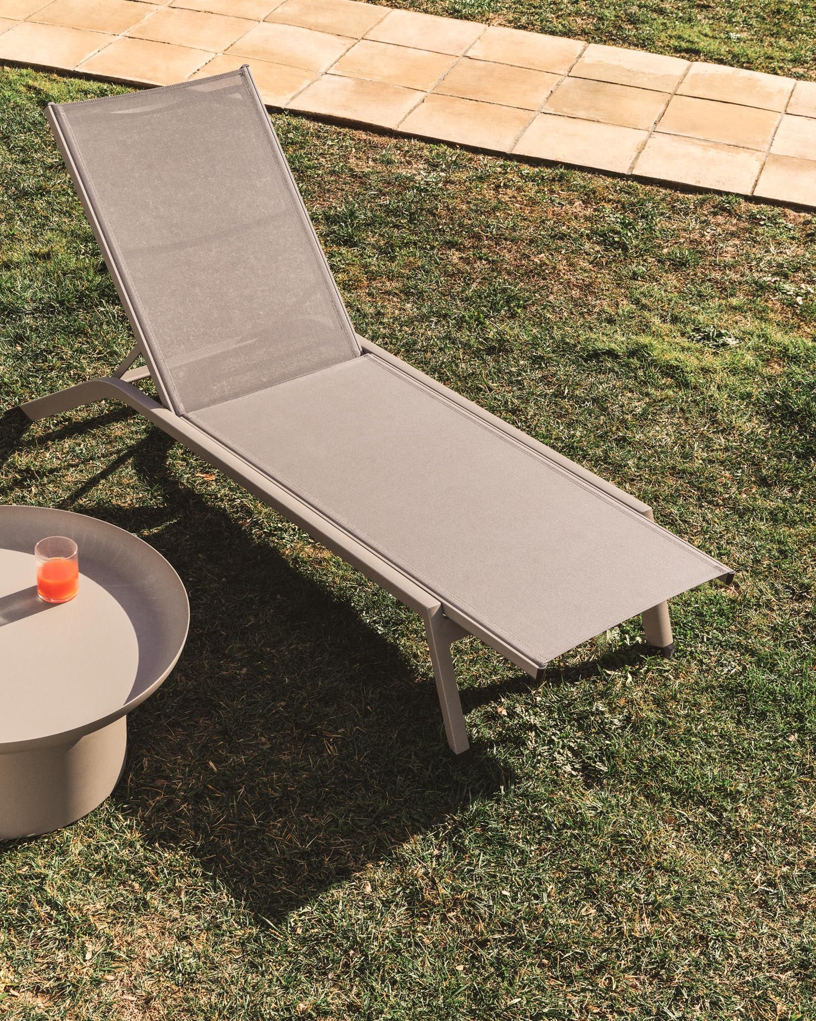 Elegante stapelbare Sonnenliege Capraia aus robustem Aluminium in stilvollem Taupe und braunem Textil, ideal für entspannte Stunden im Freien.