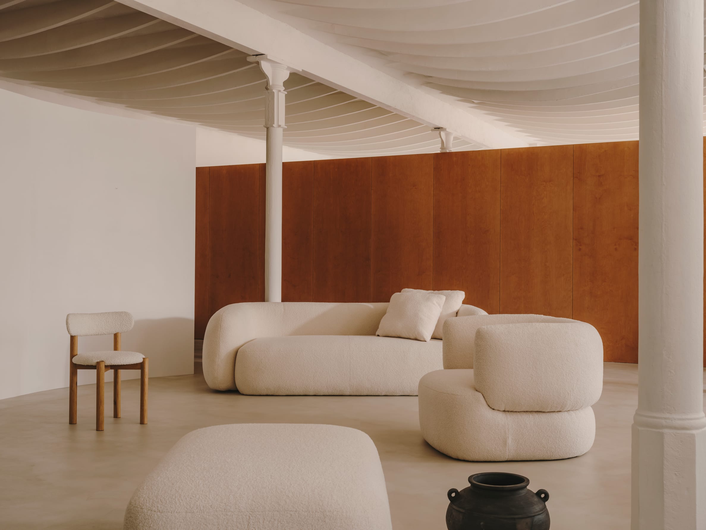 Sessel Magira: Weisser Bouclé-Stoff trifft auf dunkles Eichenholz, ein stilvolles Möbelstück für moderne Wohnräume.