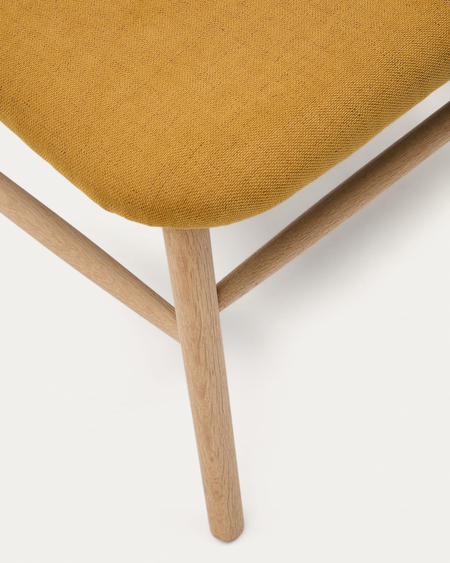 Der Sessel Helda vereint eleganten Chenille-Stoff in Senfgelb mit nachhaltigem Eichenholz und setzt stilvolle Akzente in jedem Raum.