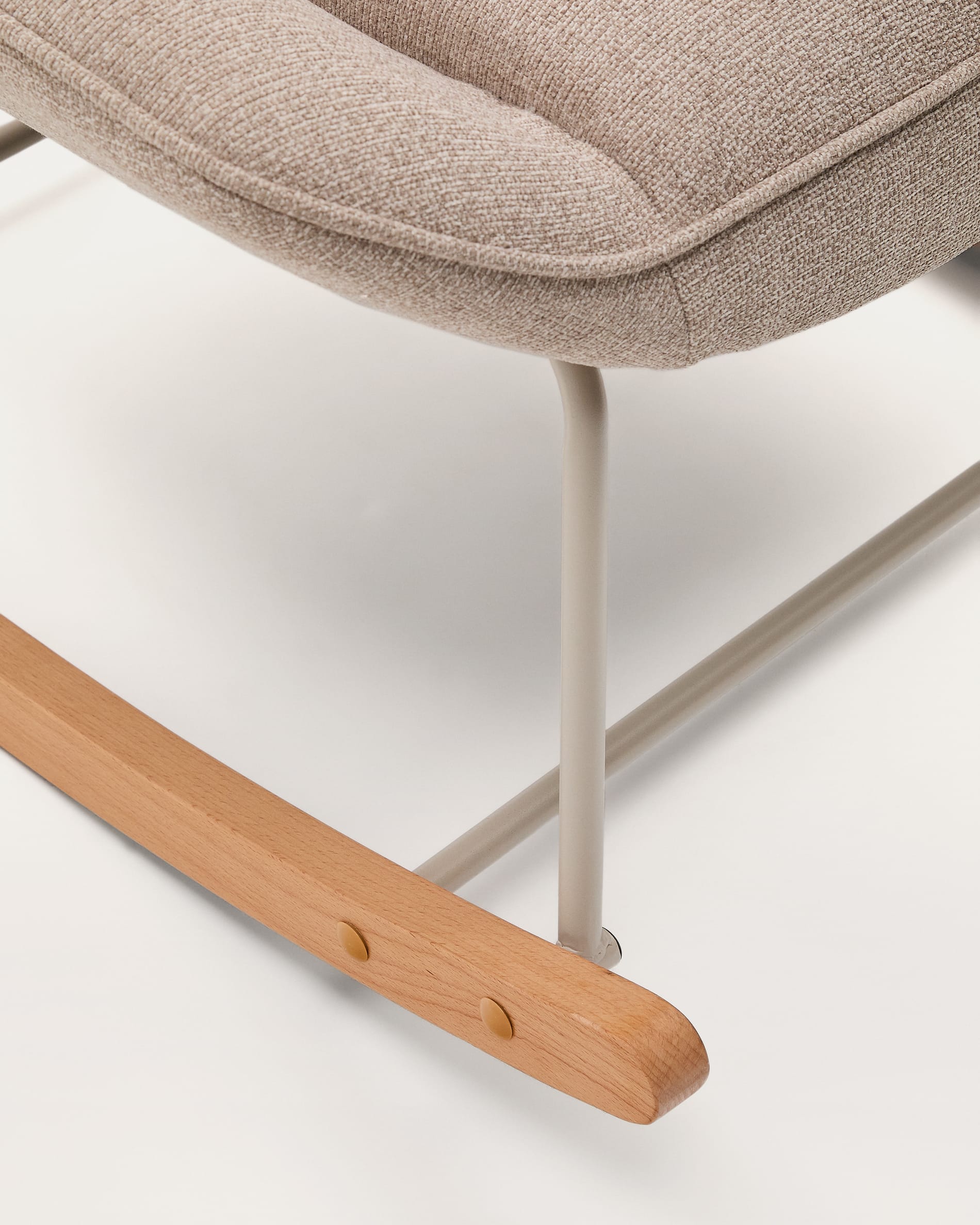 Der Schaukelstuhl Marlina kombiniert eleganten beigefarbenen Chenille-Stoff mit einem stabilen, mattgrauen Metallgestell und bietet höchsten Komfort.