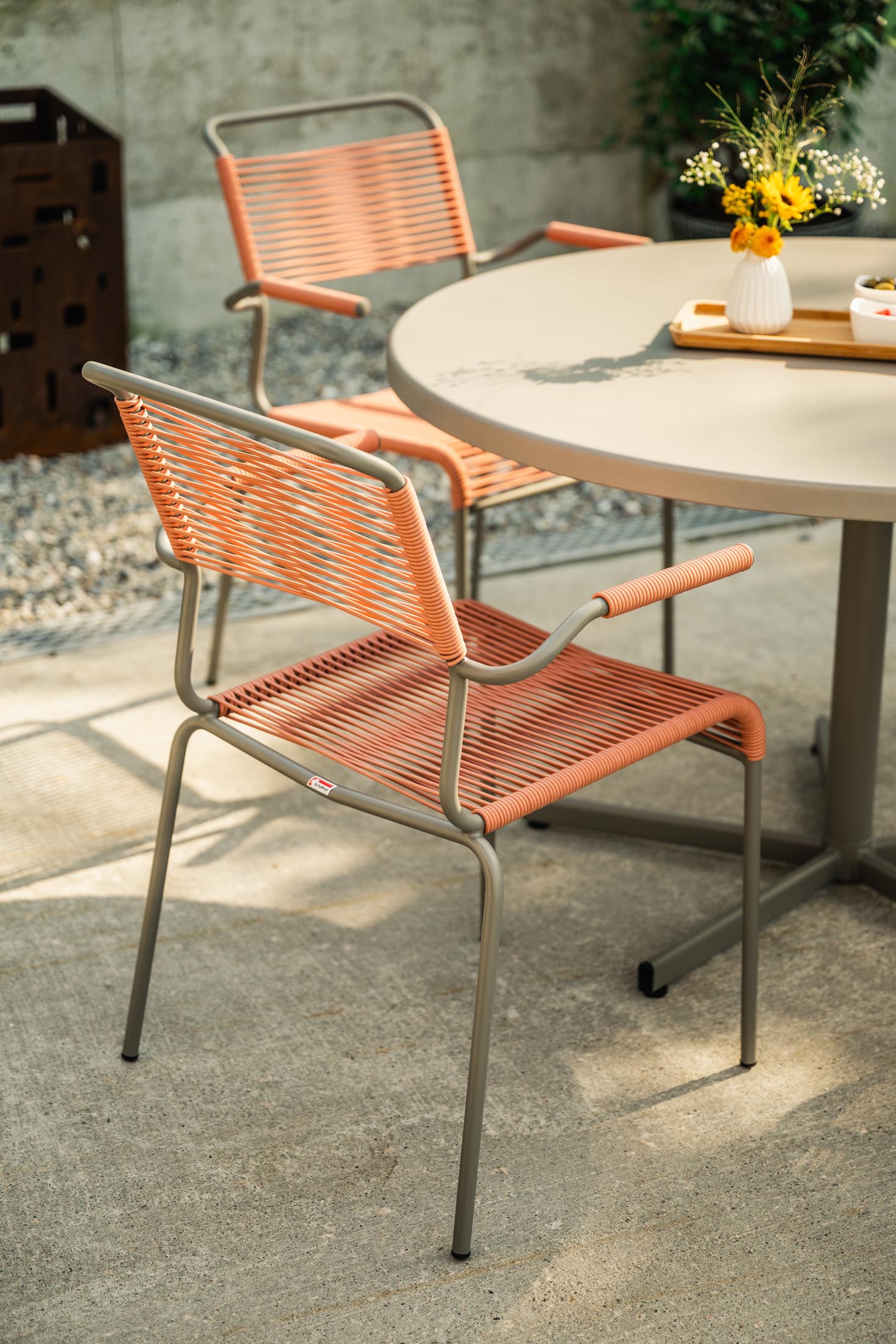 Eleganter Säntis Spaghetti-Gartenstuhl mit Armlehne aus wetterfestem, langlebigem Material. Schweizer Qualität, nachhaltiges Design und vielseitige Farboptionen.