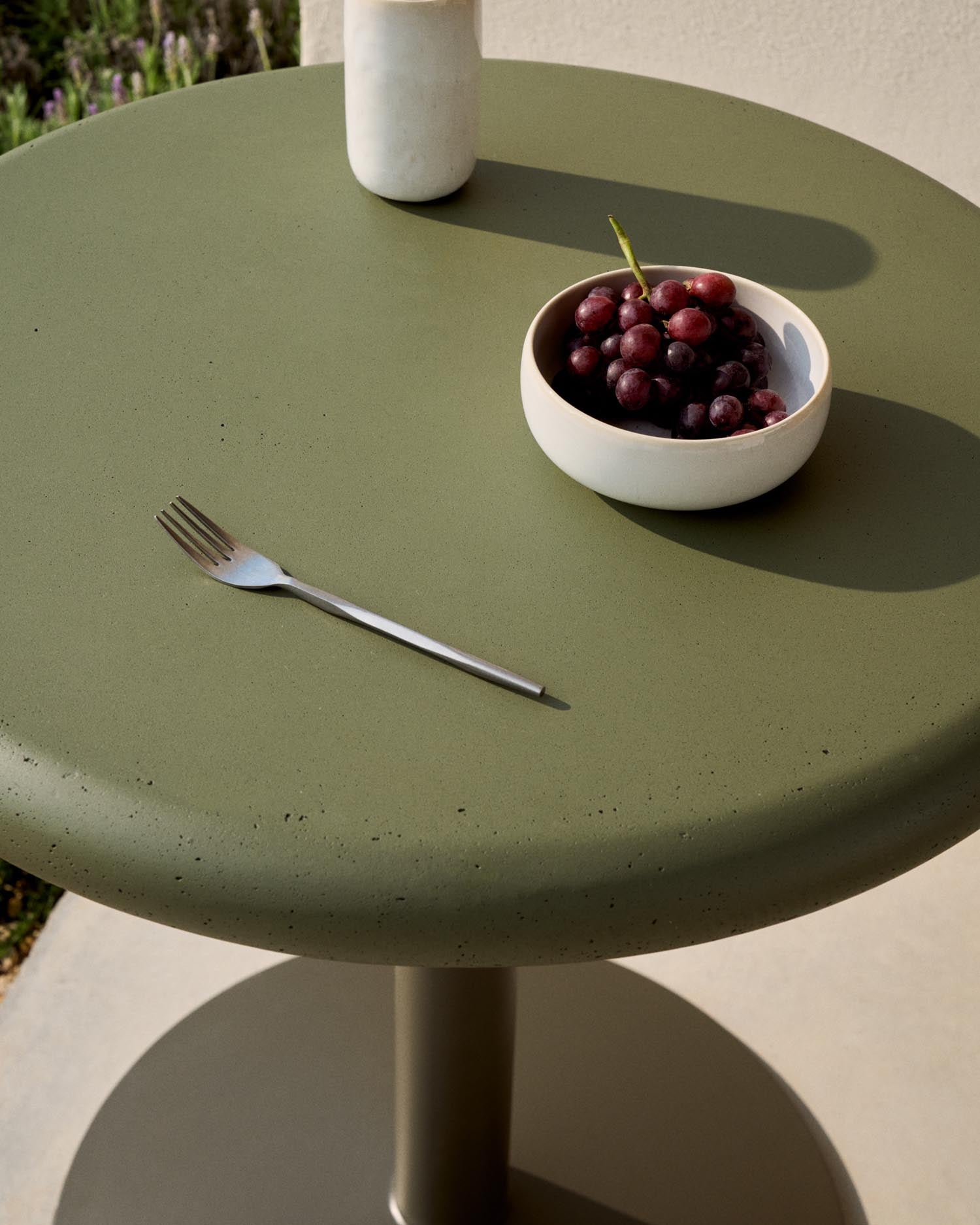 Erleben Sie den runden Outdoor-Tisch Esilda von Kave Home – ein elegantes Möbelstück mit grünem Zement und stabilem Stahlfuß, perfekt für jeden Außenbereich.