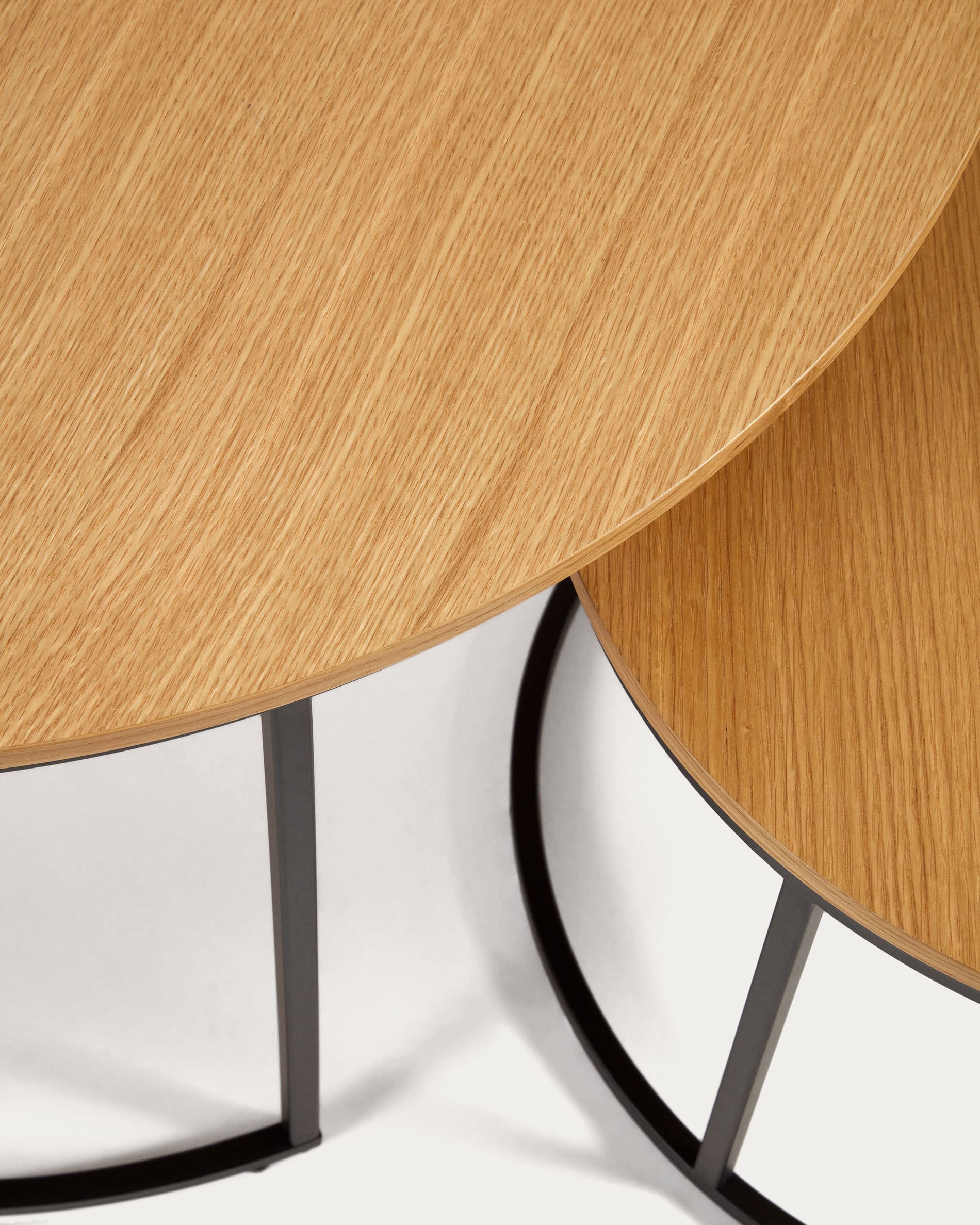 Entdecken Sie das Yoana Set: Zwei stilvolle Beistelltische aus Eichenfurnier und robustem, schwarz lackiertem Metall – ideal für moderne Wohnkonzepte.