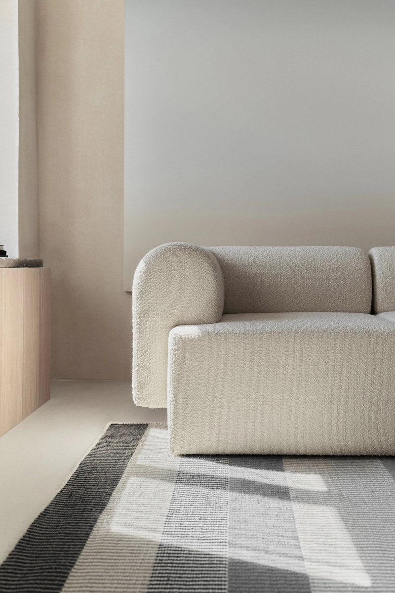 Modulares Sofa Tori von Tamo in Anthrazit mit gepolsterter Sitzfläche, abgerundeter Rückenlehne und Kunststofffüssen.