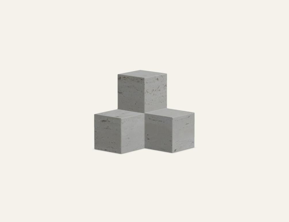 Buchstütze Tero aus Travertin in der Farbe Travertin Romano, geometrische Form mit natürlicher Maserung, auf hellem Untergrund fotografiert.