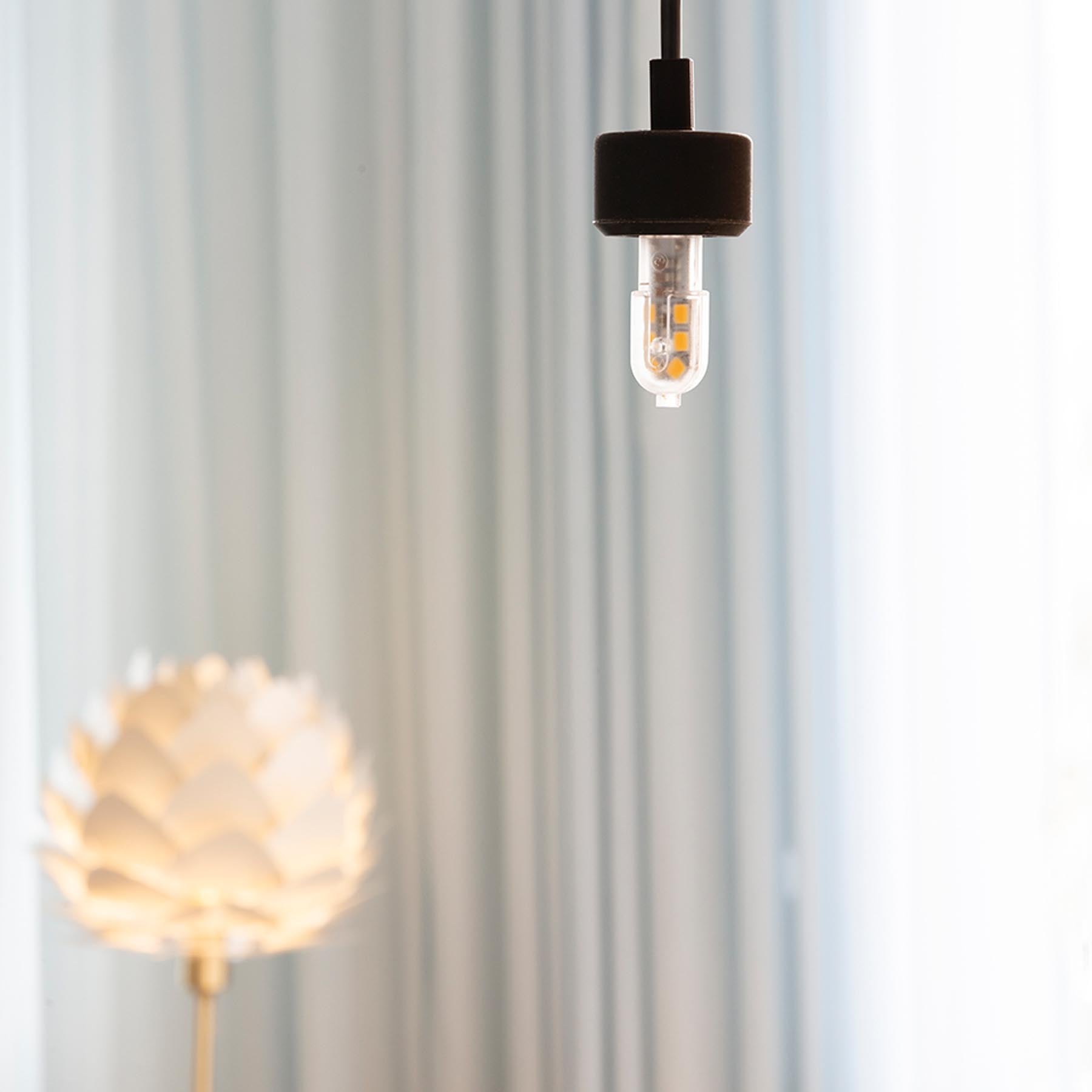 Stimmungsvolles Bild des Tiny Idea G4 Leuchtmittels von Umage, das modernes Design und warmes Licht in einem eleganten Raum vereint.