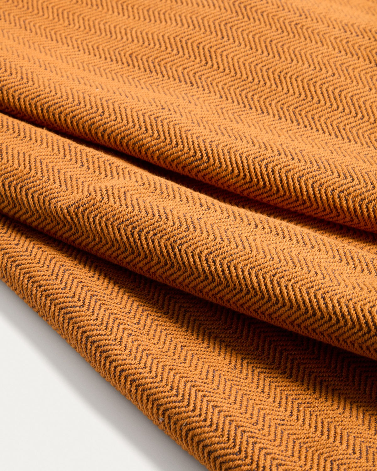 Tischläufer Tieva aus Baumwolle mit eingewebtem Jacquard-Muster in Senfgelb-Orange, rechteckige Form, 50 x 150 cm, auf einem Tisch drapiert.