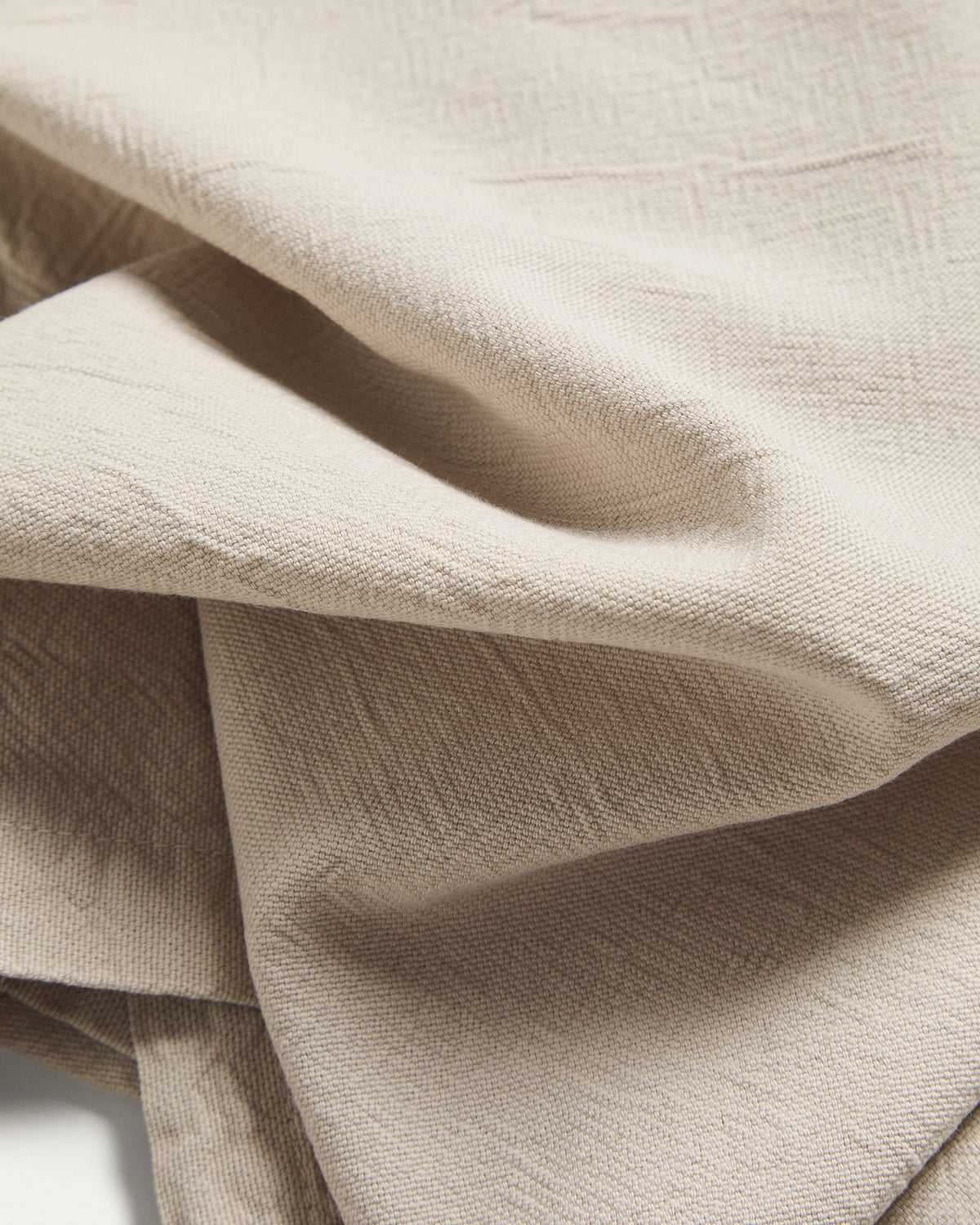 Zwei Tischsets aus Baumwolle mit steingrauem Washed-Finish und Leinen-Look, rechteckige Form, auf einem Tisch drapiert.