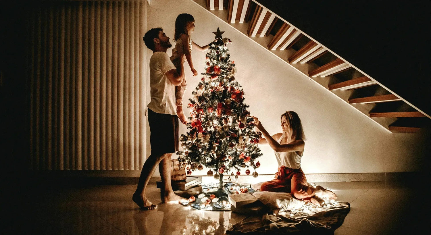 Zauberhafte weihnachtliche Inneneinrichtung: warme Beleuchtung, gemütliche Decken, geschmückter Baum und festlich gedeckter Esstisch.