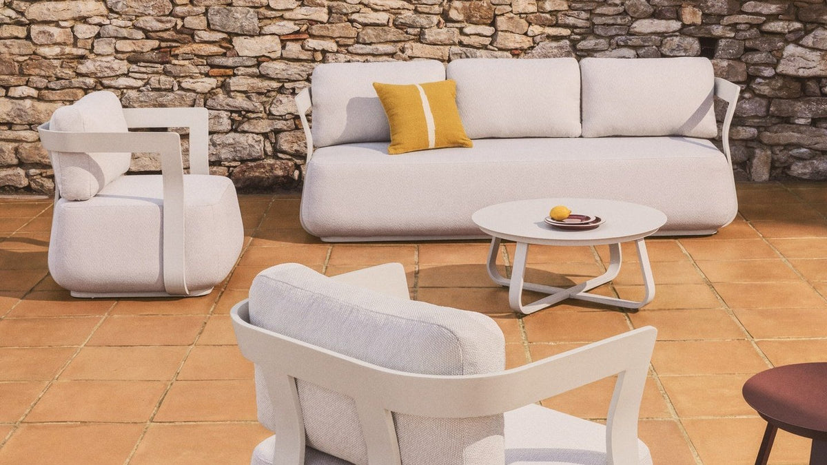 Loungeset Tamaris von Kave Home mit 3-Sitzer-Sofa und zwei Sesseln aus ecrufarbenem Aluminium auf einer Terrasse