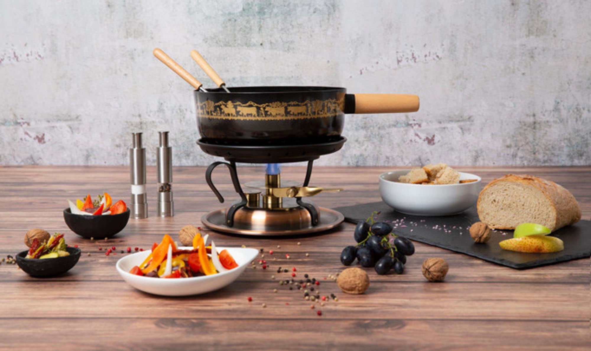 Elegante STÖCKLI Käsefonduegarnitur mit Kupfer-Finish, induktionsgeeignet, auf stabilem Buchenholzständer. Perfekt für gesellige Fondueabende.