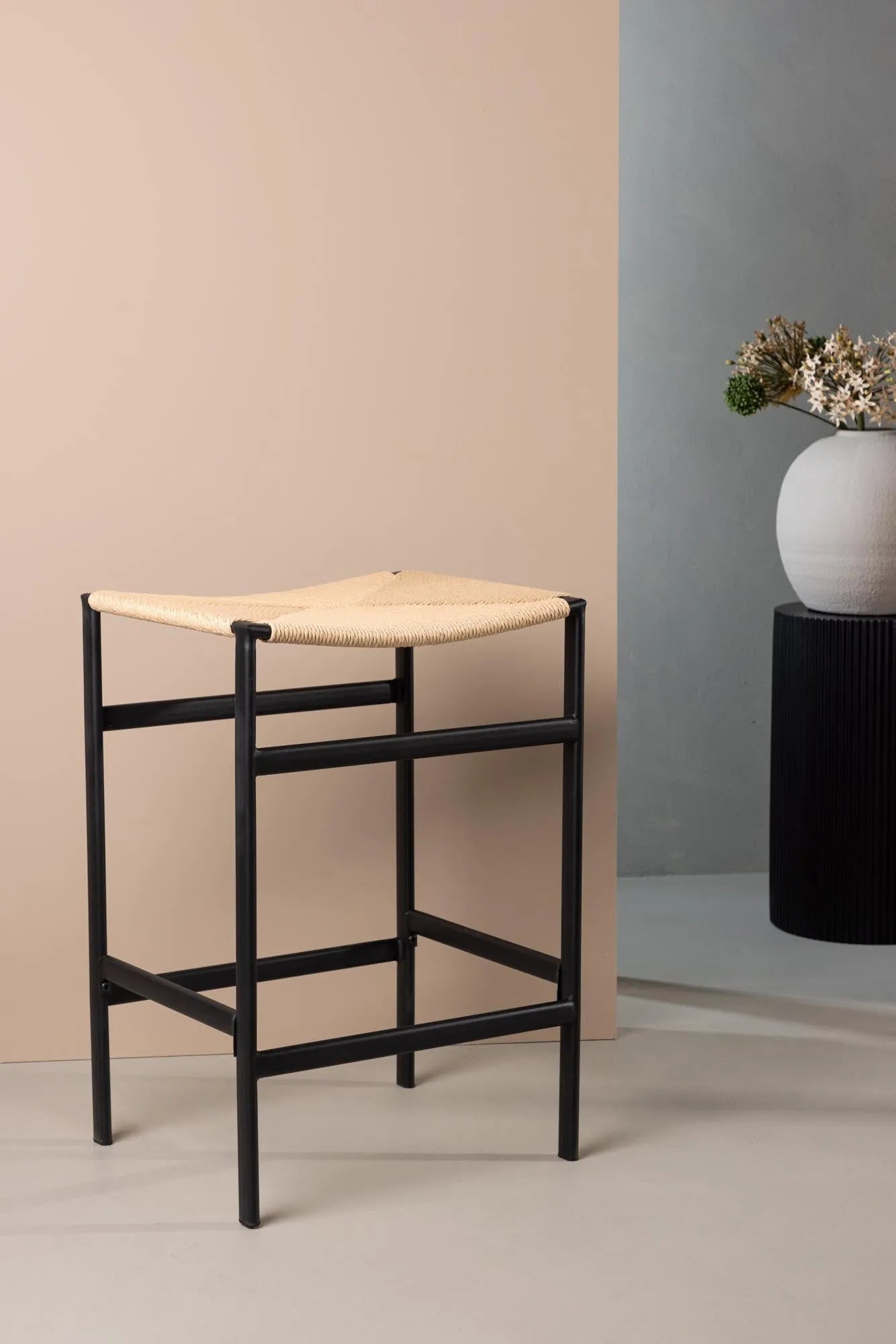 Der Polly Barstuhl vereint Rattan-Sitz und weiße Holzbeine zu einem stilvollen, platzsparenden Design für modernen Boho-Chic.