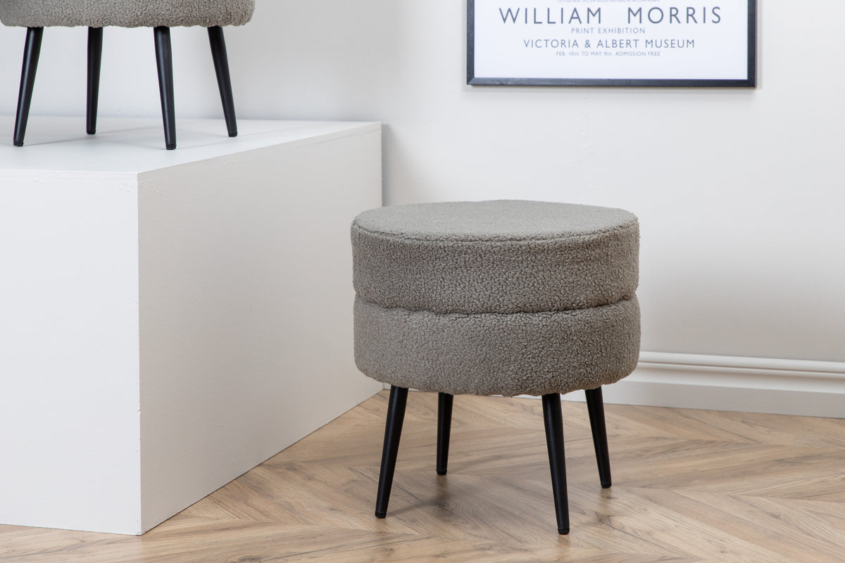 Runder Pouf Pot in Grau mit Teddystoff-Bezug, Durchmesser 40 cm, auf schwarzen, leicht ausgestellten Stahlbeinen stehend.