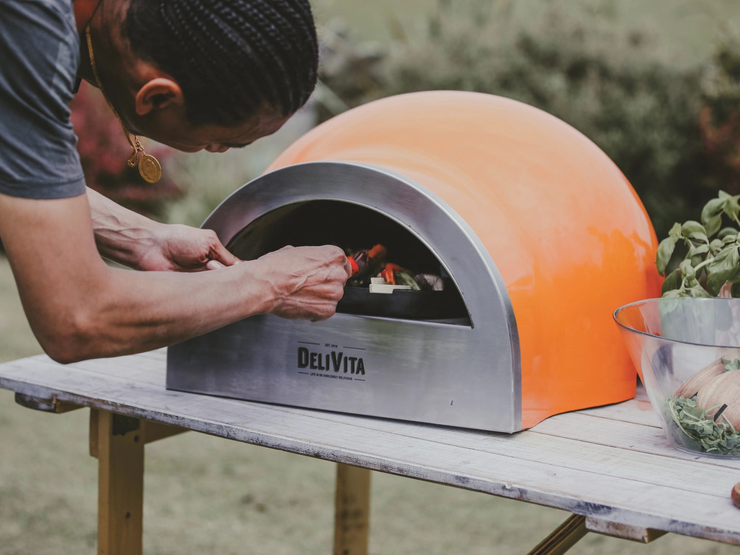 Kompakter, orangefarbener Pizzaofen von Delivita, perfekt für Outdoor-Pizza-Events, vereint Funktionalität und modernes Design.