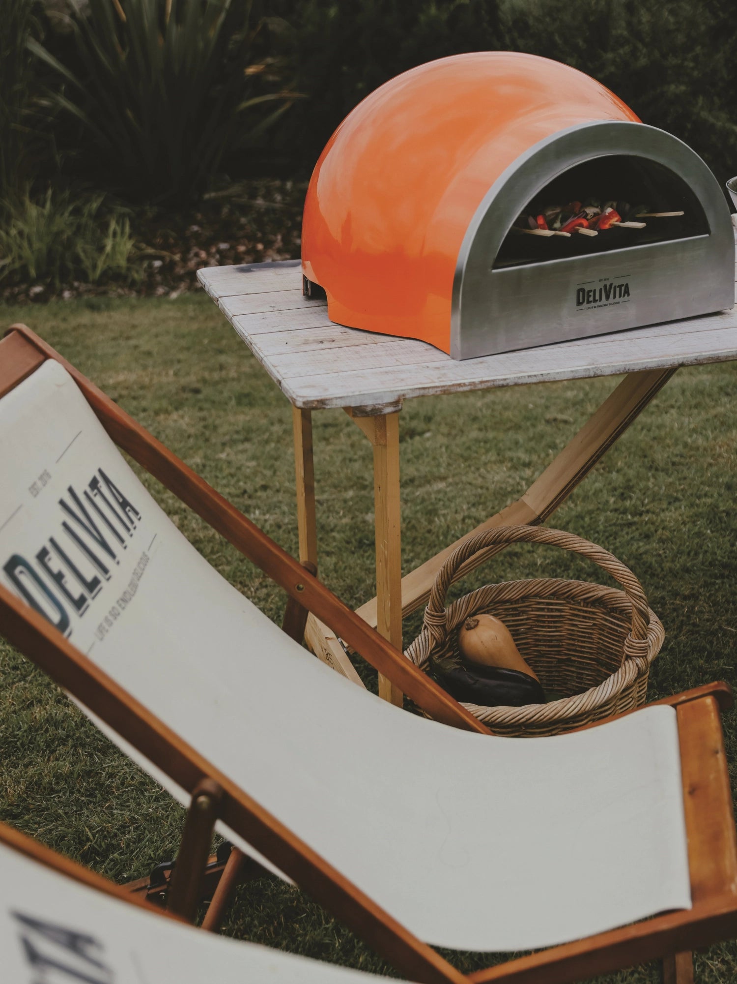 Leuchtend orangefarbener Pizzaofen von Delivita, ideal für Gartenpartys, bietet hohe Leistung und stilvolles Design für perfekte Pizzagenüsse.