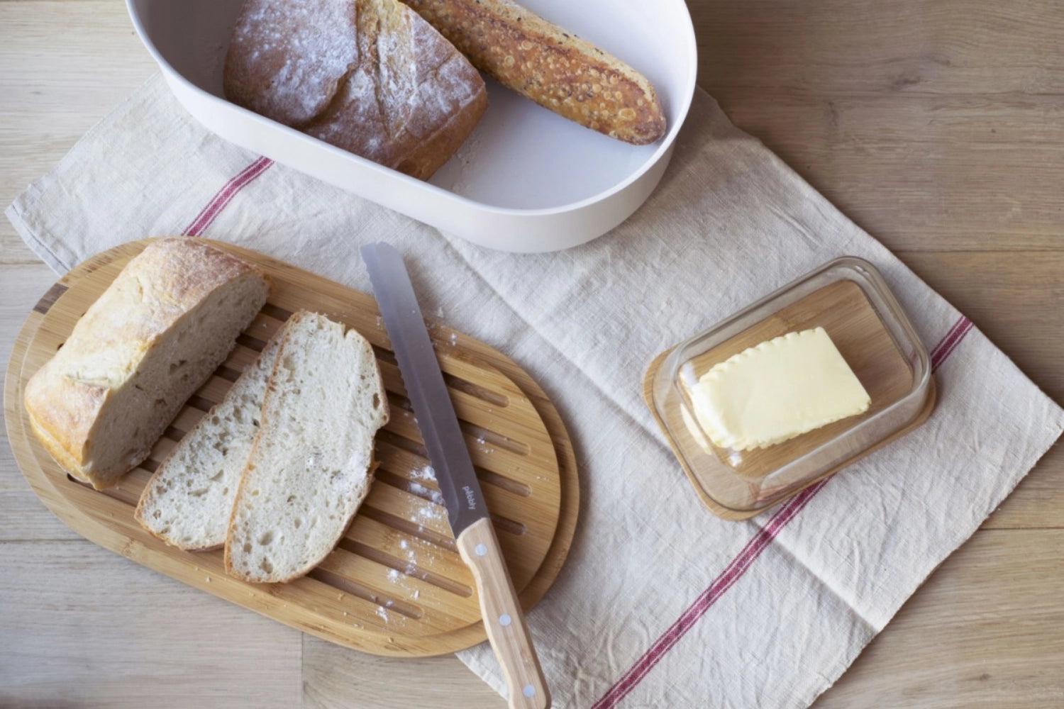 Eleganter Pebbly Brotkasten mit Schneidebrett, Messer und Brotbeutel in Cream, ideal für frisches Brot und stilvolle Küchen.