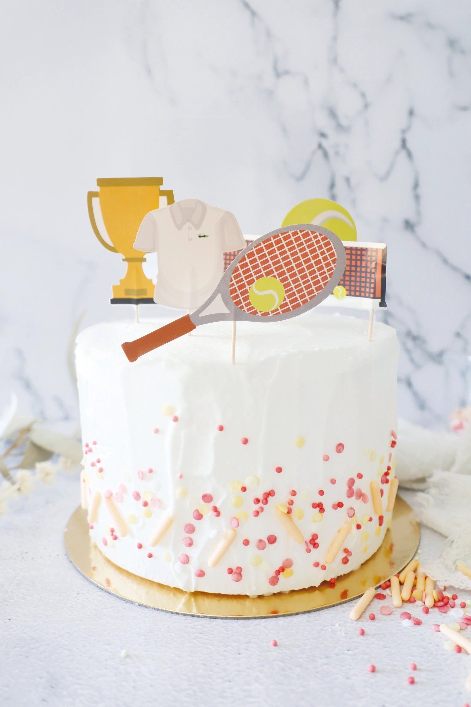 Fünf originelle Kuchendekorationen mit Tennis-Motiven aus Papier, perfekt für sportliche Feiern und kreative Backprojekte.