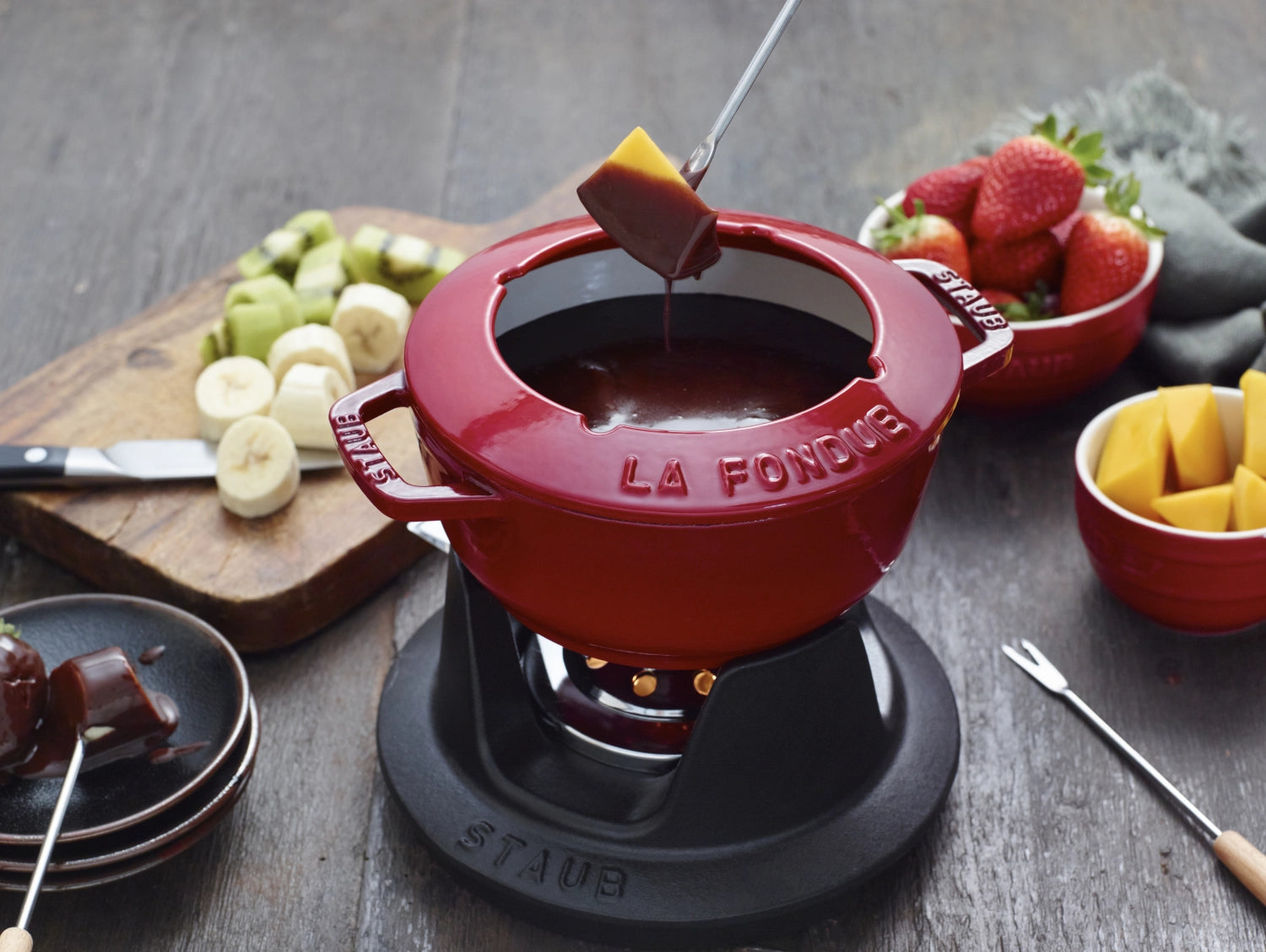 Rundes Fondue Set in Kirsch-Rot von Staub, 16 cm, mit zwei praktischen Griffen. Perfekt für gesellige Fondue-Abende und stilvolles Servieren.