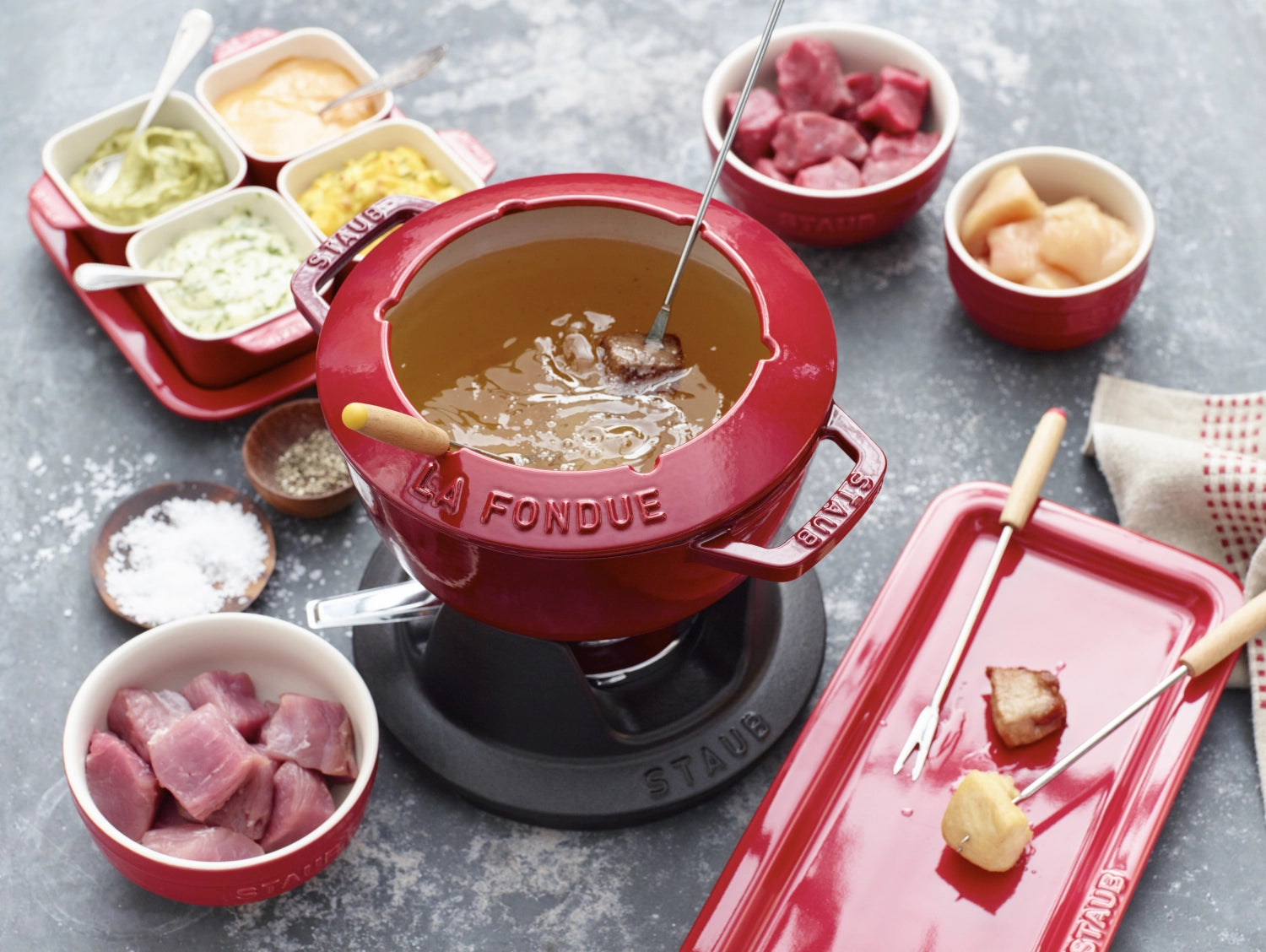 Rundes Fondue Set in Kirsch-Rot von Staub, 18 cm, mit zwei praktischen Griffen – perfekt für gesellige Fondue-Abende.