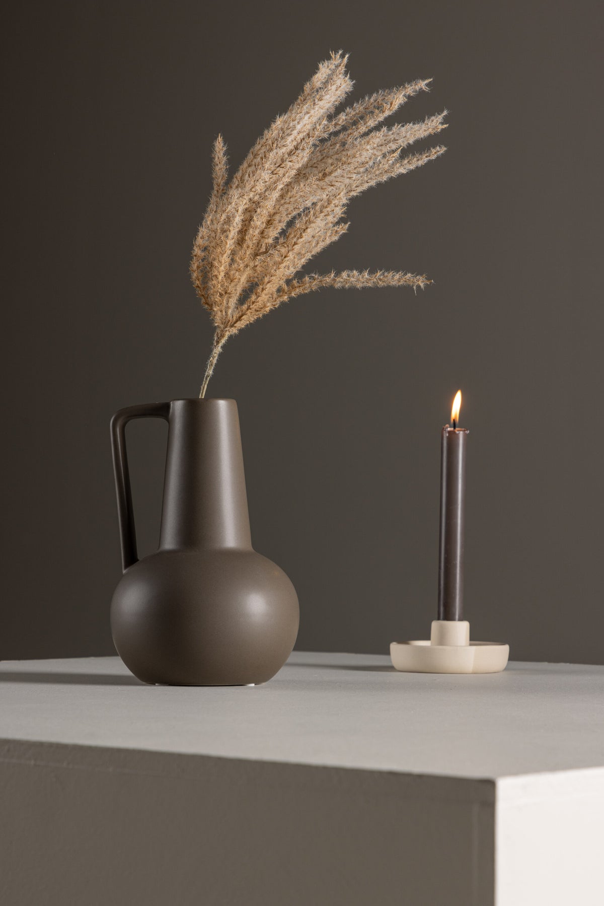 Zylindrische Vase aus Steinzeug in Beige und Schwarz mit seitlichem Griff, matte Oberfläche, Höhe 22 cm, Durchmesser 10 cm.