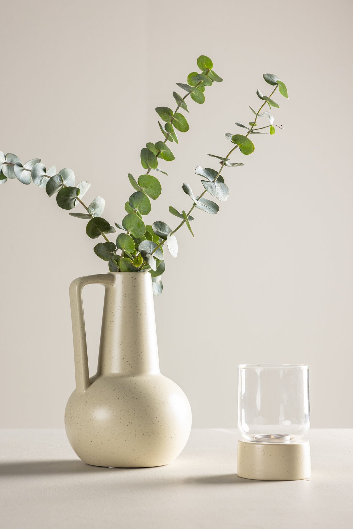 Zylindrische Vase aus Steinzeug in Beige und Schwarz mit seitlichem Griff, matte Oberfläche, Höhe 22 cm, Durchmesser 10 cm.