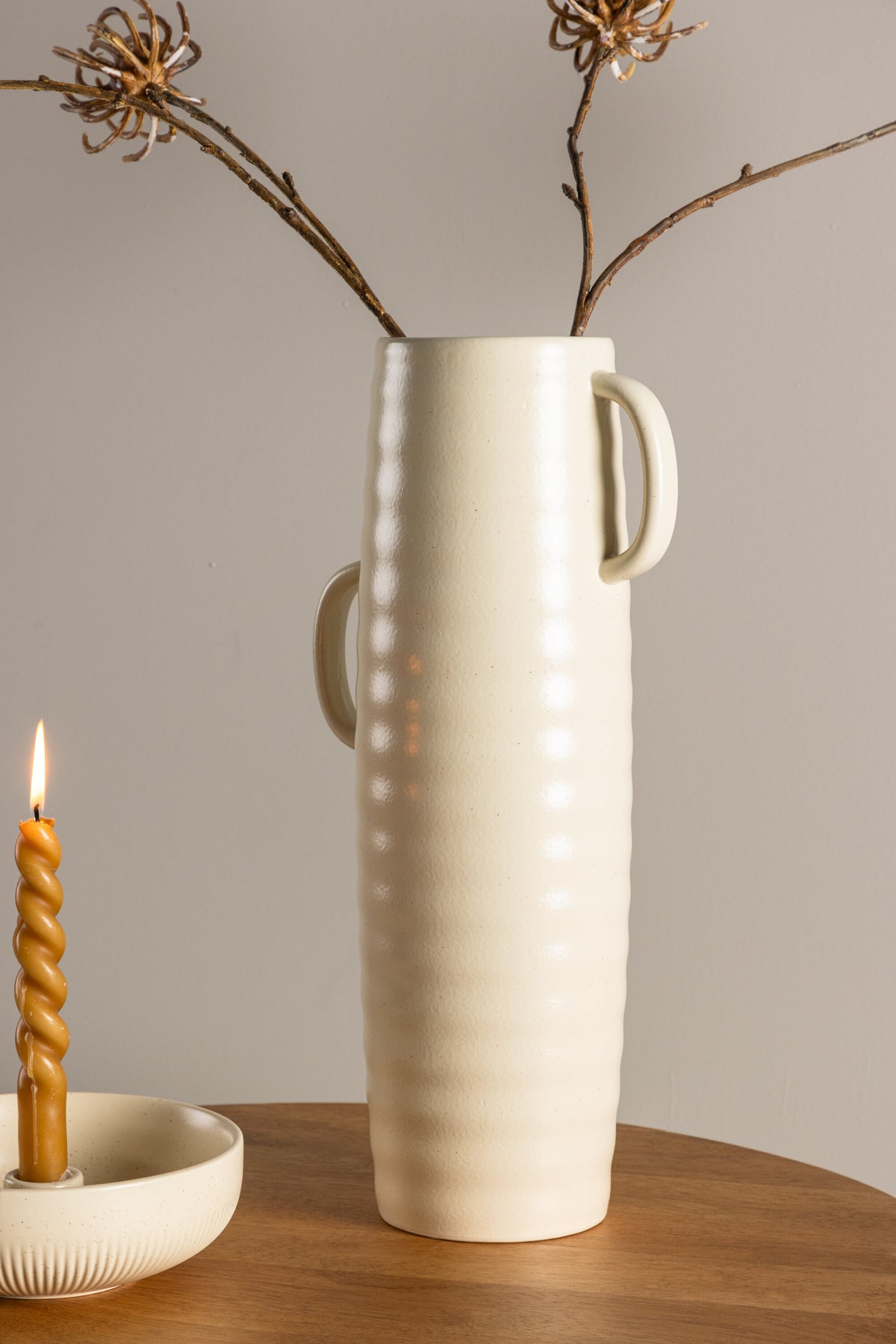 Beige Cent Vase von Venture Home aus Steinzeug mit wellenförmiger Struktur und zwei asymmetrisch angebrachten Griffen an den Seiten.