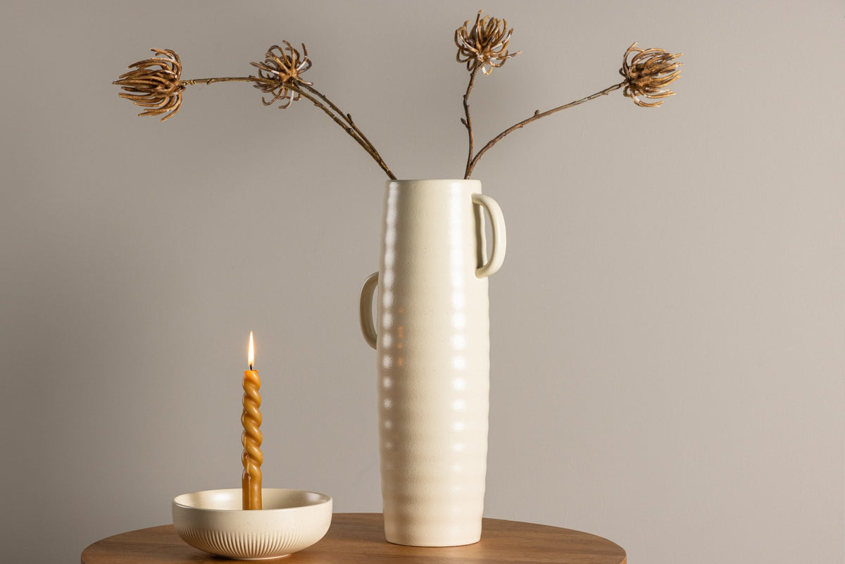 Beige Cent Vase von Venture Home aus Steinzeug mit wellenförmiger Struktur und zwei asymmetrisch angebrachten Griffen an den Seiten.