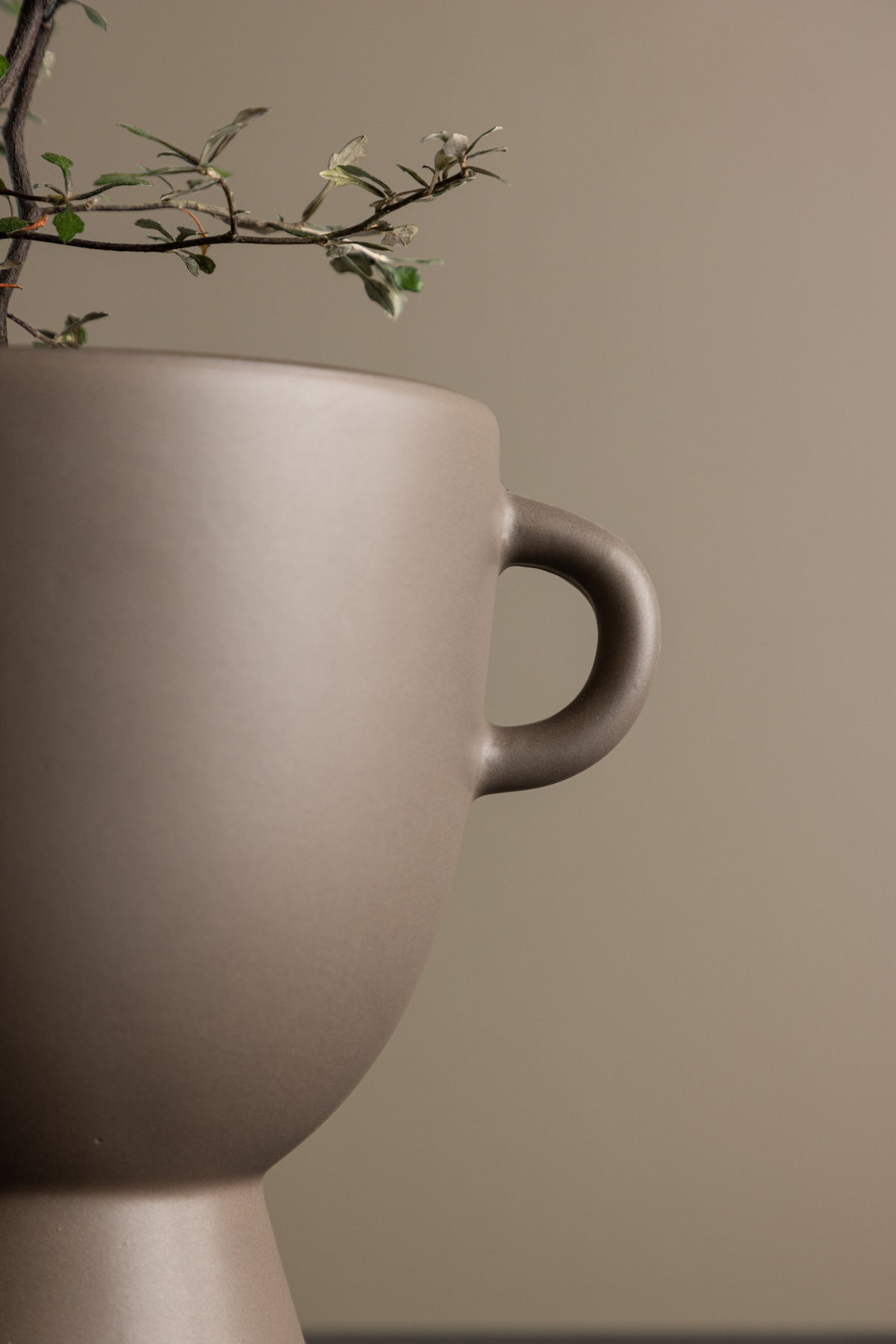 Beige Cent Vase von Venture Home aus Steinzeug mit wellenförmiger Struktur und zwei asymmetrisch angebrachten Griffen an den Seiten.