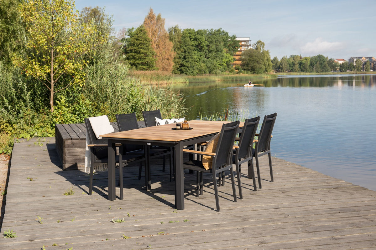 Rechteckiger Gartentisch Mexiko mit naturfarbener Teakholz-Tischplatte und schwarzem Aluminiumgestell, ausziehbar, im Freien aufgestellt.